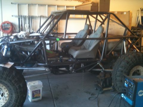 1966 Ford Bronco - A custom-built buggy with a roll cage and off-road tires sits in a workshop, undergoing modifications.