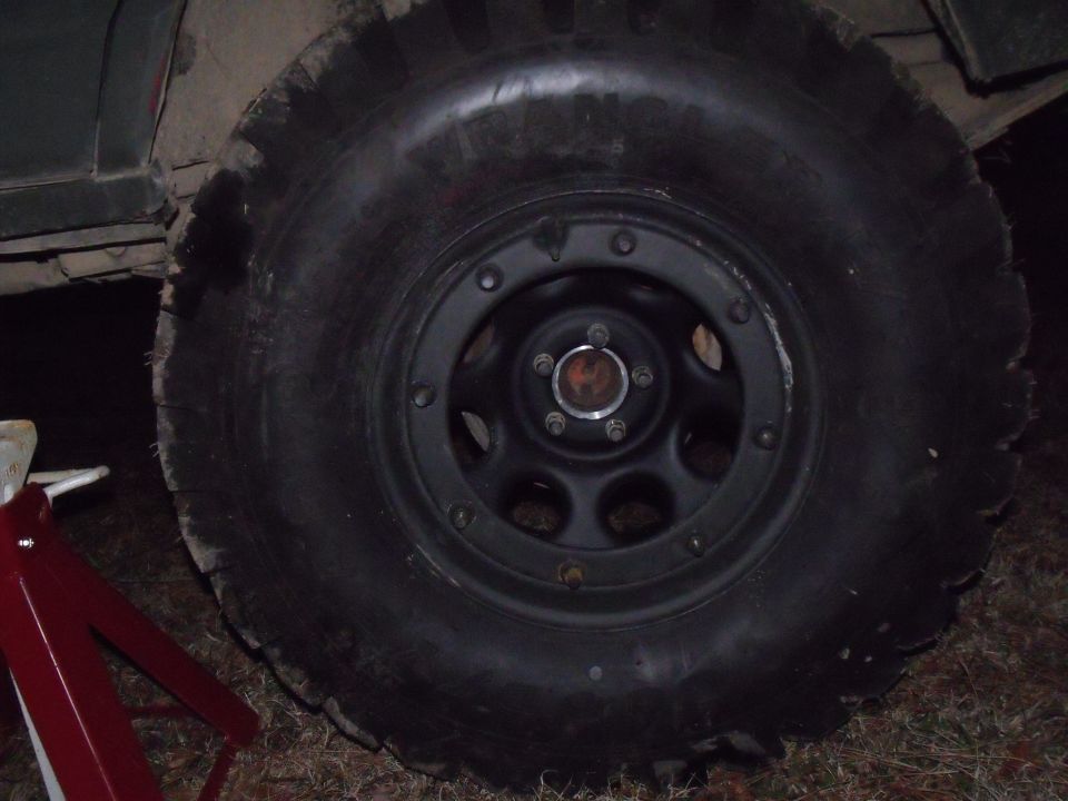 1992 Jeep Cherokee wheel with aggressive off-road tire, jack stand visible