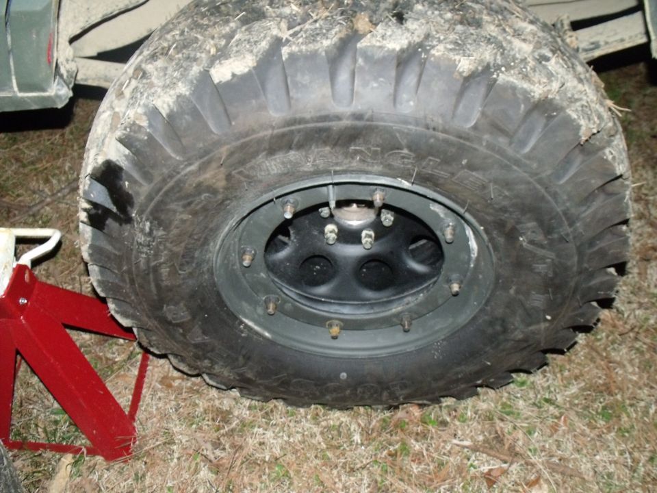 Close-up of a large off-road tire and black wheel, supported by red jack stands
