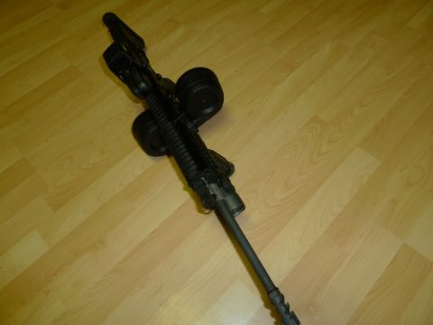 1992 Ford Mustang - An assault rifle with a large capacity drum magazine rests on a light wood floor.