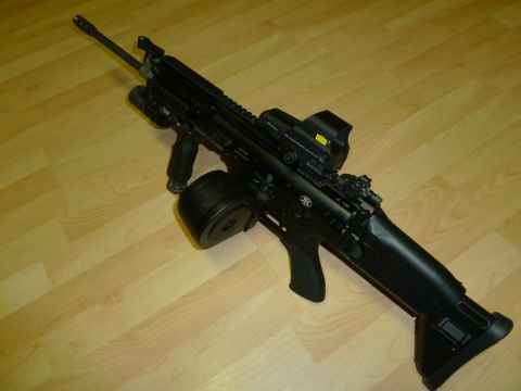 1992 Ford Mustang - An assault rifle with a drum magazine and optical sight is displayed on a wooden surface.