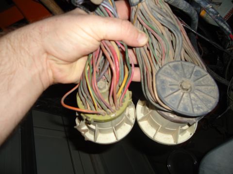1987 Ford F-150 - Two large wiring harness connectors with numerous colored wires are held in a hand.