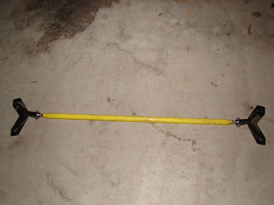Yellow strut bar with black Y-shaped end mounts on concrete floor