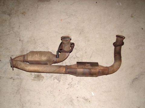 1992 Ford Taurus - This is an exhaust system part, likely a catalytic converter assembly, resting on a concrete surface.