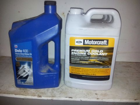 1990 Chevrolet Suburban - Two bottles of automotive fluids, one motor oil and one engine coolant, sit on a shelf.