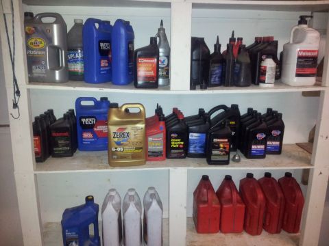 1990 Chevrolet Suburban - A collection of automotive fluids are neatly organized on white shelves.