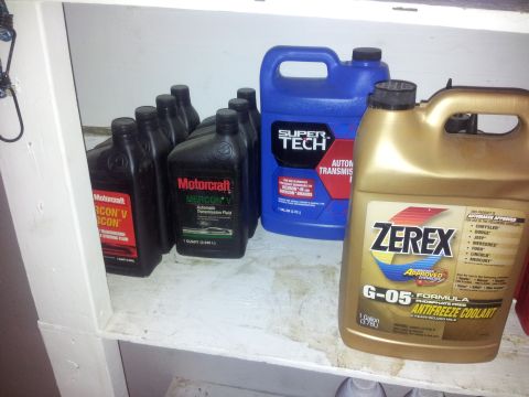 1990 Chevrolet Suburban - Various automotive fluids, including transmission fluid and antifreeze, are stored on a shelf.