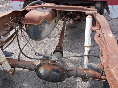 1987 Ford Ranger - The rear suspension and fuel tank assembly of a heavily rusted truck chassis is visible.