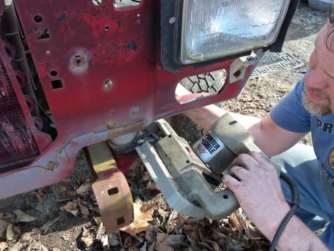 1987 Ford Ranger - A person uses a Porter-Cable saw to cut a section of a red 1987 Ford Ranger fender during a tear-down process.