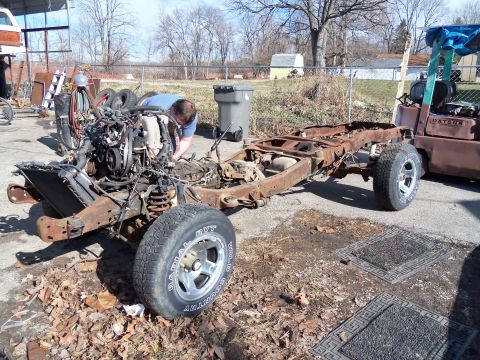 1987 Ford Ranger - Disassembled 1987 Ford Ranger chassis and engine in a yard. A person is actively working on the engine.
