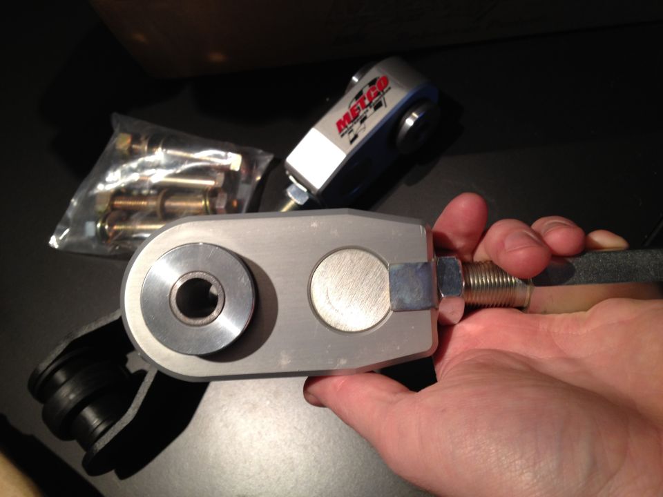 Hand holding a Metco control arm with a bag of bolts in the background