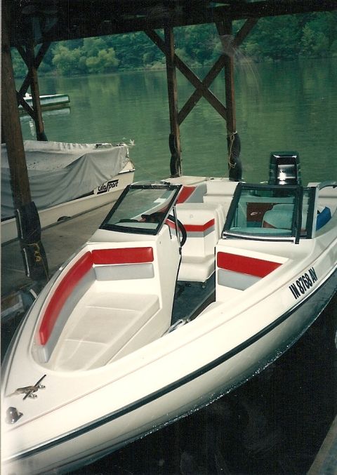 1987 Ford Ranger - A white speed boat with red accents is docked under a covered slip on a lake.