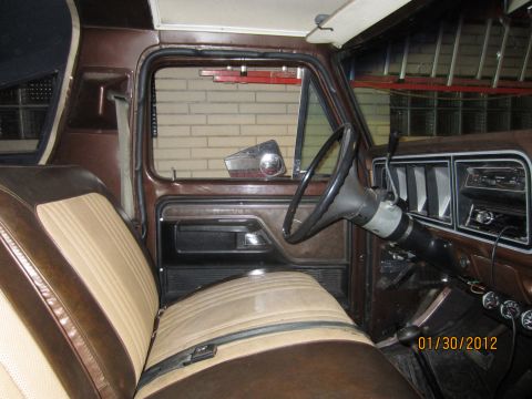 1979 Ford Bronco - The interior of an older vehicle, two-tone seats and a dashboard with a radio and gauges.