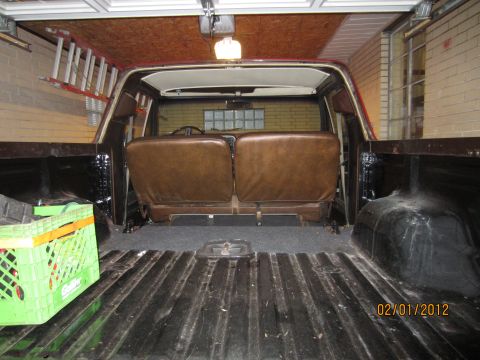 1979 Ford Bronco - The interior of a 1978 Ford Bronco shows brown vinyl seats and a dark bed liner, with a green crate visible.