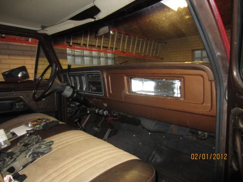 1979 Ford Bronco - The interior of a 1979 Ford Bronco shows its brown dashboard and tan seats, with a ladder visible through the windshield.