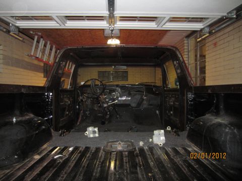 1979 Ford Bronco - The interior of a truck is shown disassembled in a garage, with the dashboard removed and parts scattered.