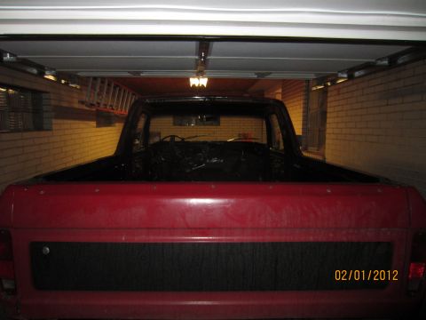 1979 Ford Bronco - Interior view of a red pickup truck, showing the dashboard and steering wheel, parked inside a garage.
