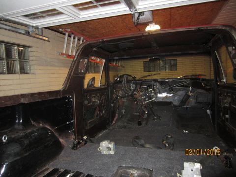 1979 Ford Bronco - The interior of a vehicle is shown with the dashboard and seats removed, revealing exposed wiring and the bare cabin structure.