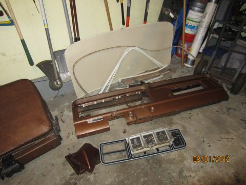 1979 Ford Bronco - Vehicle interior parts, including a dashboard and seat, are disassembled and stored on a garage floor.