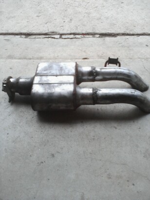 1989 Ford Bronco - Dual exhaust system with a central muffler and two curved pipes, resting on a concrete surface.