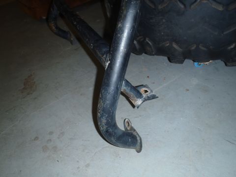 1979 Ford Bronco - Close-up of a black metal tube assembly next to a large tire on a concrete floor.
