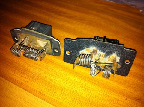 1998 Ford Crown Victoria - Two blower motor resistors are shown on a wooden surface, one with visible rust and metal coils.