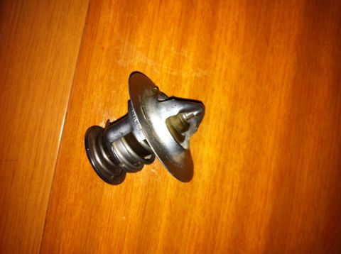 1998 Ford Crown Victoria - A car thermostat is shown on a wooden background.