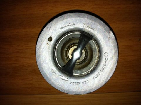 1998 Ford Crown Victoria - A close-up view of a car thermostat, identified by its part number and manufacturer.