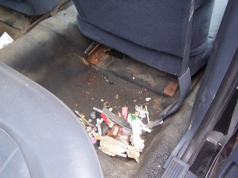 2001 Ford Crown Victoria - The interior of a vehicle is littered with trash and drug paraphernalia on the floor near the seats.