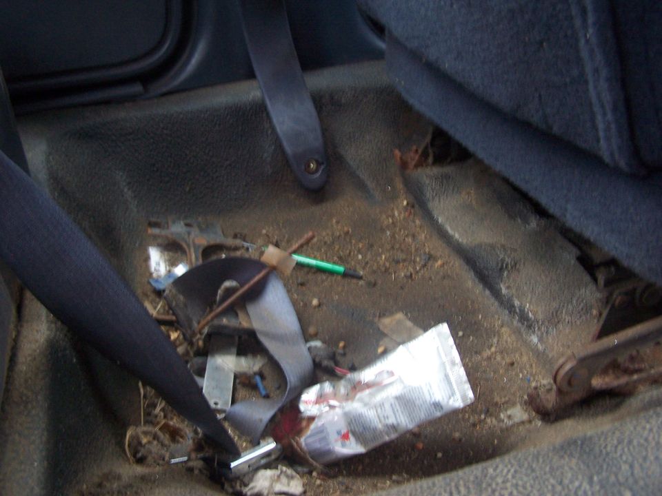 Car interior floor with debris, seatbelt, and a tube of ointment