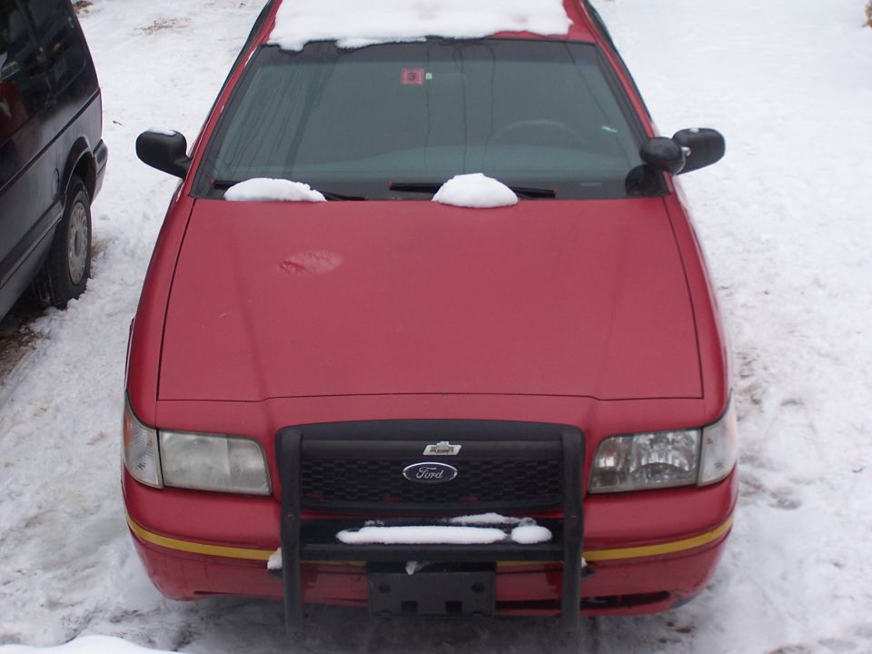 Red Ford Crown Victoria with black push bar, front view, snow on hood and roof