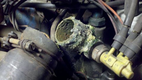 1978 Ford Bronco - Close-up of a heavily corroded engine component, showing extensive mineral deposits and wear.