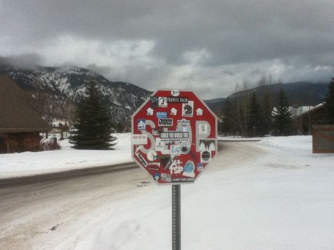 2006 Ford E350 - A stop sign, adorned with numerous stickers, stands in a snow-covered landscape under a cloudy sky.