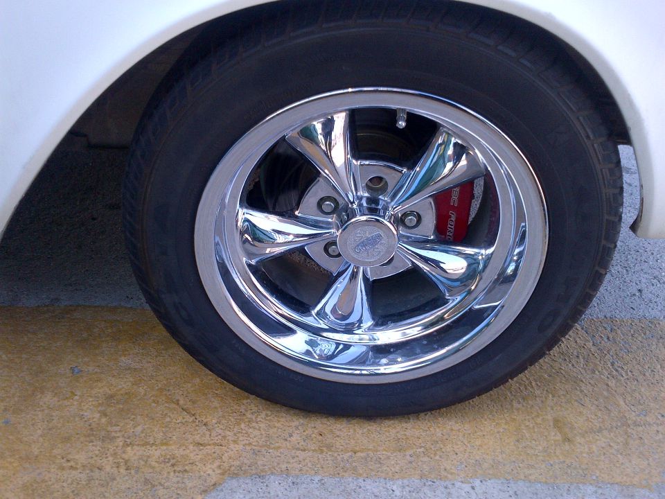 Chrome five-spoke wheel with red brake caliper visible behind spokes. Supermotors.net logo at bottom right