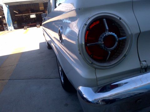 1965 Ford Mustang - A white 1963 Ford Falcon is viewed from the rear quarter panel, showing its distinctive taillight and chrome bumper.
