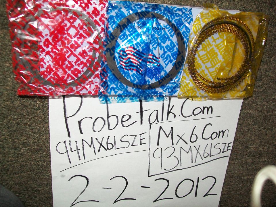 Three sets of piston rings in red, blue, and yellow packaging