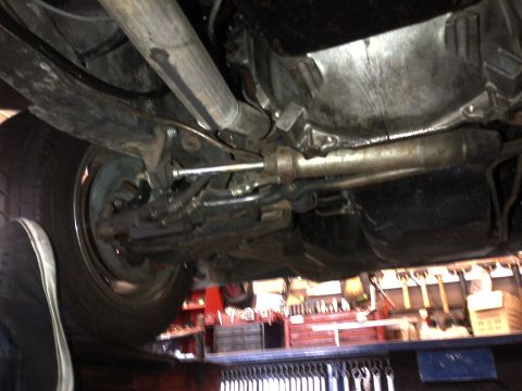 1965 Ford Mustang - Undercarriage view of a vehicle's suspension and exhaust system, with a shoe in the foreground.