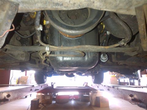 1965 Ford Mustang - The underside of a vehicle, showing the engine and drivetrain components while elevated on a lift.