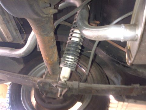 1965 Ford Mustang - Close-up of a car's rear suspension components and exhaust system, with a Supermotors logo.