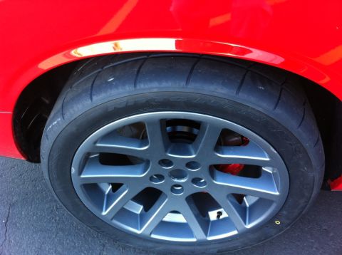 2010 Dodge Challenger - Close-up of a red car's wheel and tire, with Supermotors.net logo in the corner.