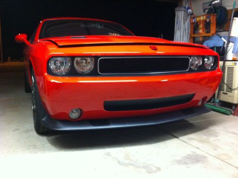 2010 Dodge Challenger - The front fascia and headlights of an orange Dodge Challenger are visible in this garage setting.