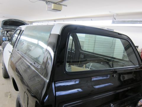 1987 Dodge 1500 - A black pickup truck cab with white trim is seen from the rear, with another vehicle in the background.