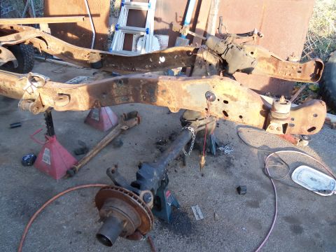 1987 Ford Ranger - A heavily rusted truck frame and suspension components are disassembled and supported by jack stands, indicating a tear-down process.