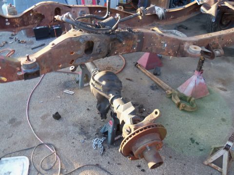 1987 Ford Ranger - The heavily rusted frame and rear axle of a vehicle are disassembled and supported by jack stands.