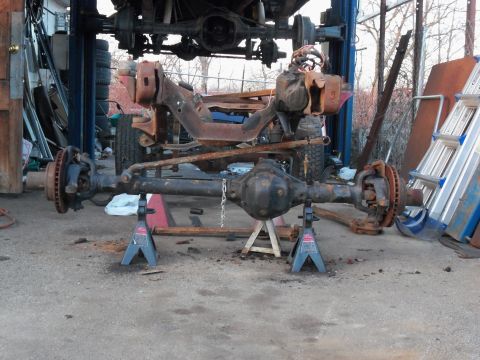 1987 Ford Ranger - Front axle assembly, likely from a truck, is disassembled and supported by jack stands in a workshop setting.