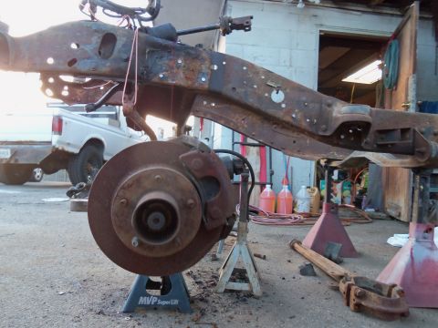 1987 Ford Ranger - Truck frame and suspension parts are on jack stands in a workshop setting. Another truck is visible in the background.
