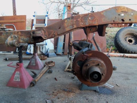 1987 Ford Ranger - This heavily rusted vehicle frame and suspension components are supported by jack stands outdoors.