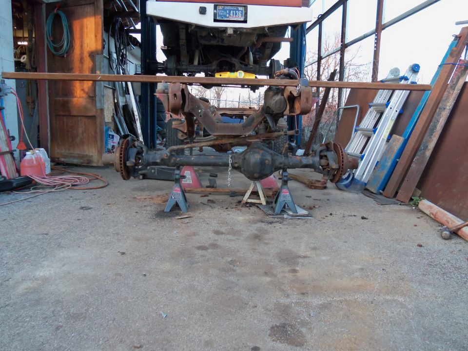 Front axle assembly on jack stands, part of a vehicle lifted above
