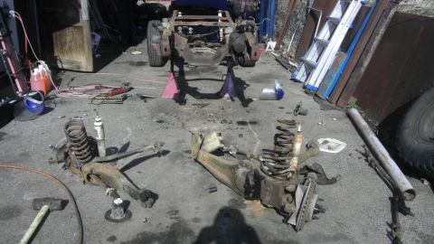 1987 Ford Ranger - Vehicle chassis and suspension parts are laid out on the ground, suggesting a repair or restoration project.