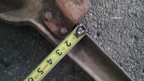 1987 Ford Ranger - A tape measure is used to measure a rusty metal part, possibly a vehicle component.